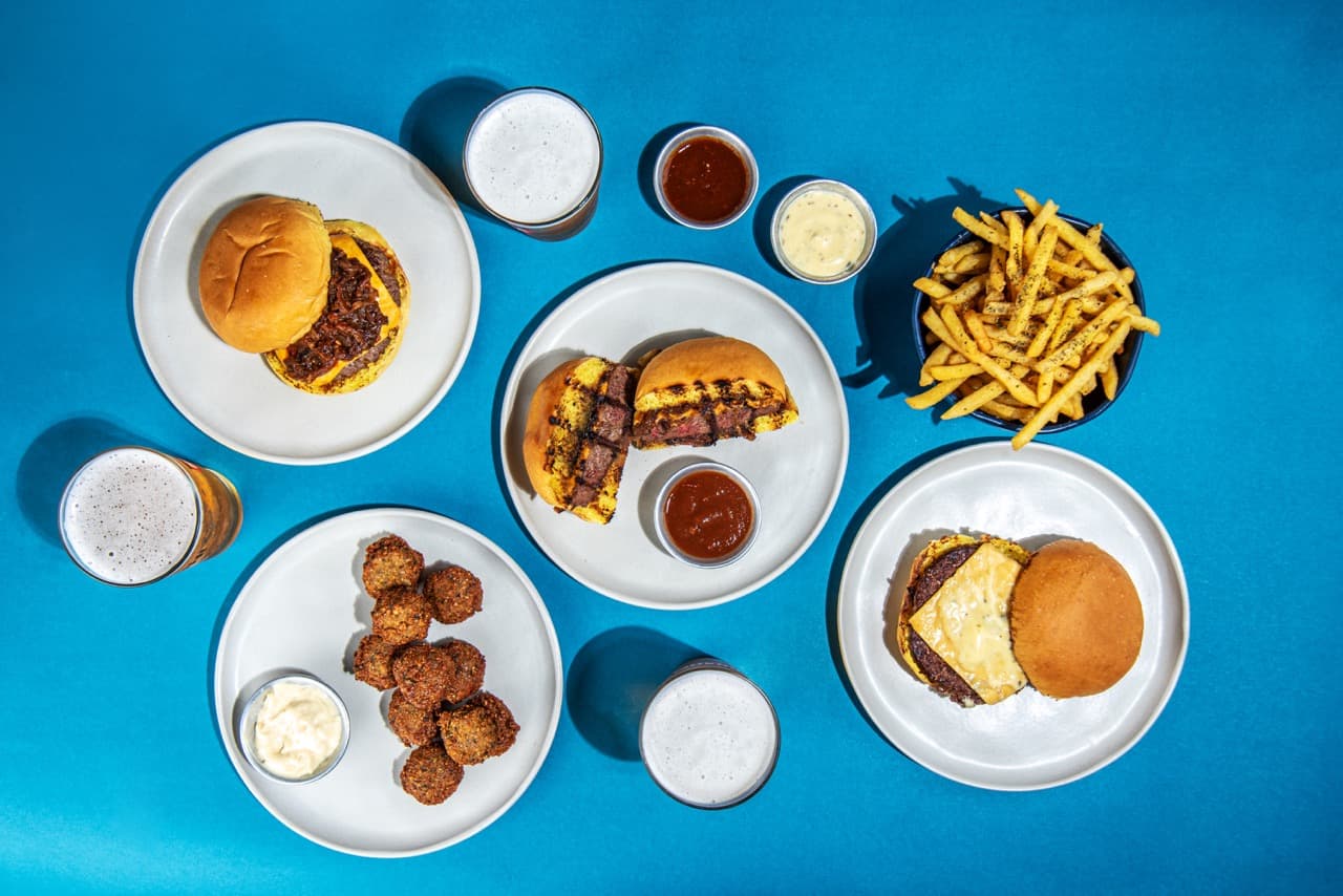 Mesa lindamente arrumada com burgers, batatas e bebidas.